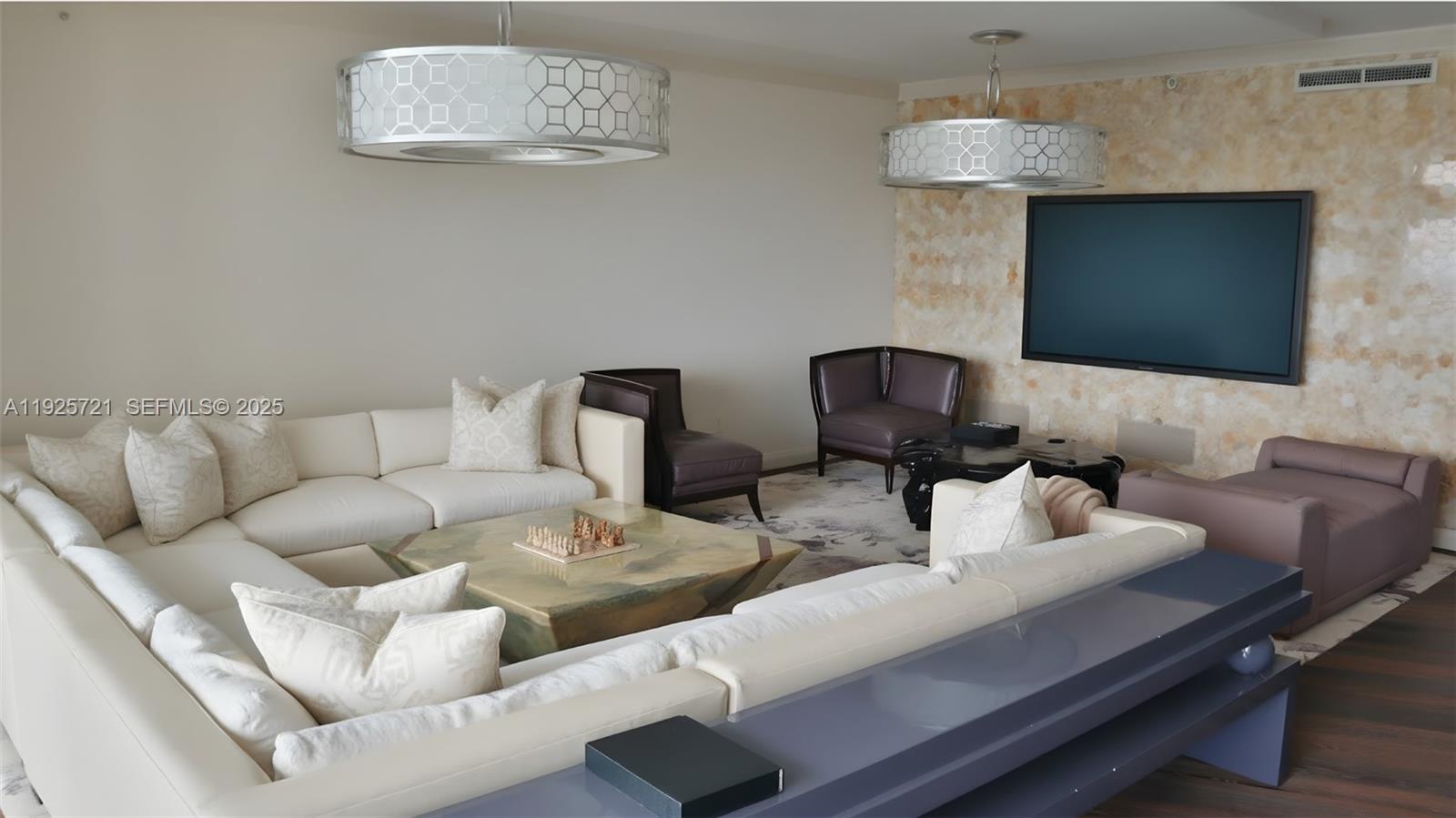 A living room features two large drum chandeliers, a white sectional sofa, and a television — 10295 Collins Ave # 1203, Bal Harbour FL 33154, BAL HARBOUR, FL