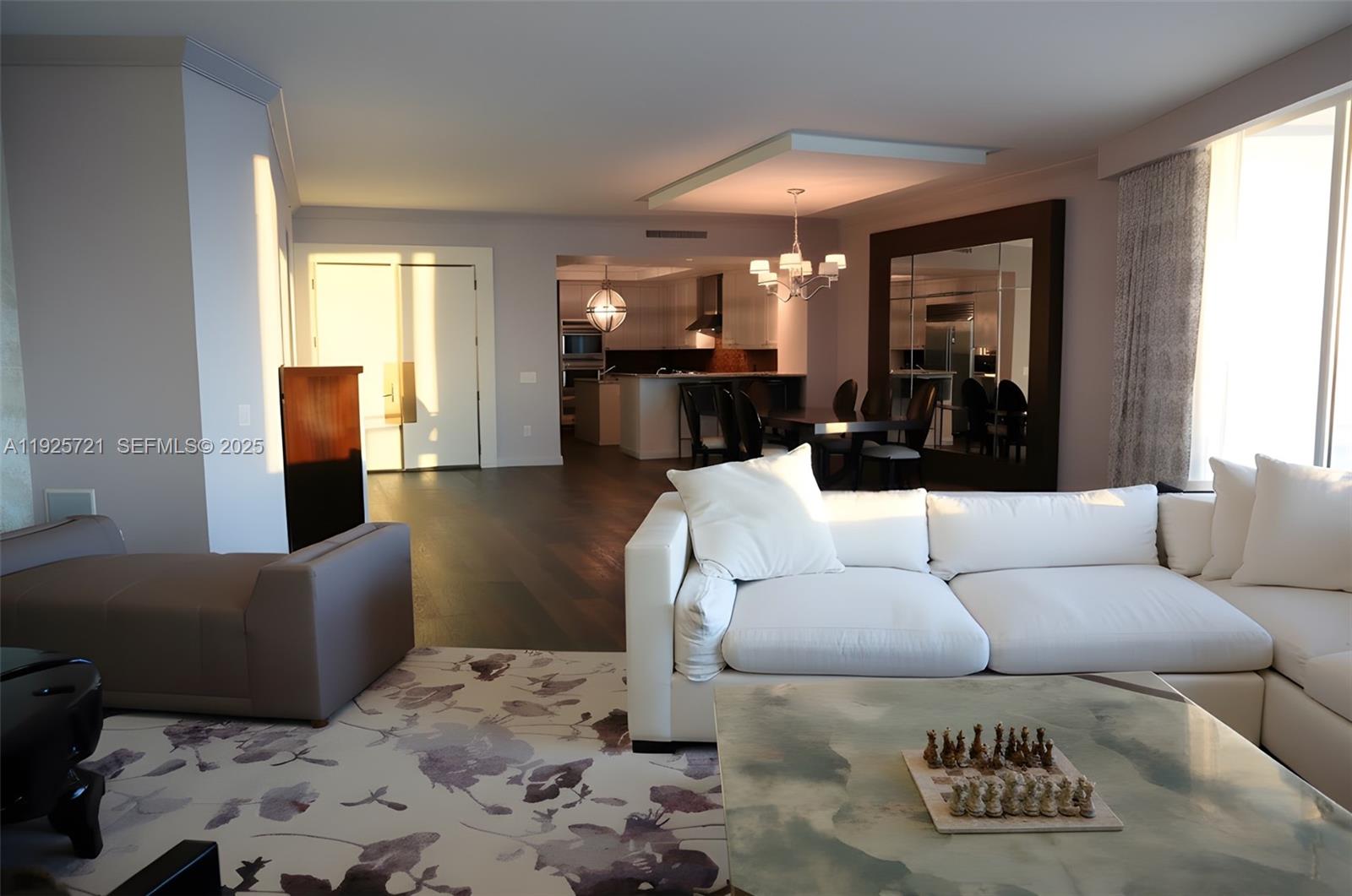 A living room features a white sectional sofa, a chess set, and an open kitchen — 10295 Collins Ave # 1203, Bal Harbour FL 33154, BAL HARBOUR, FL