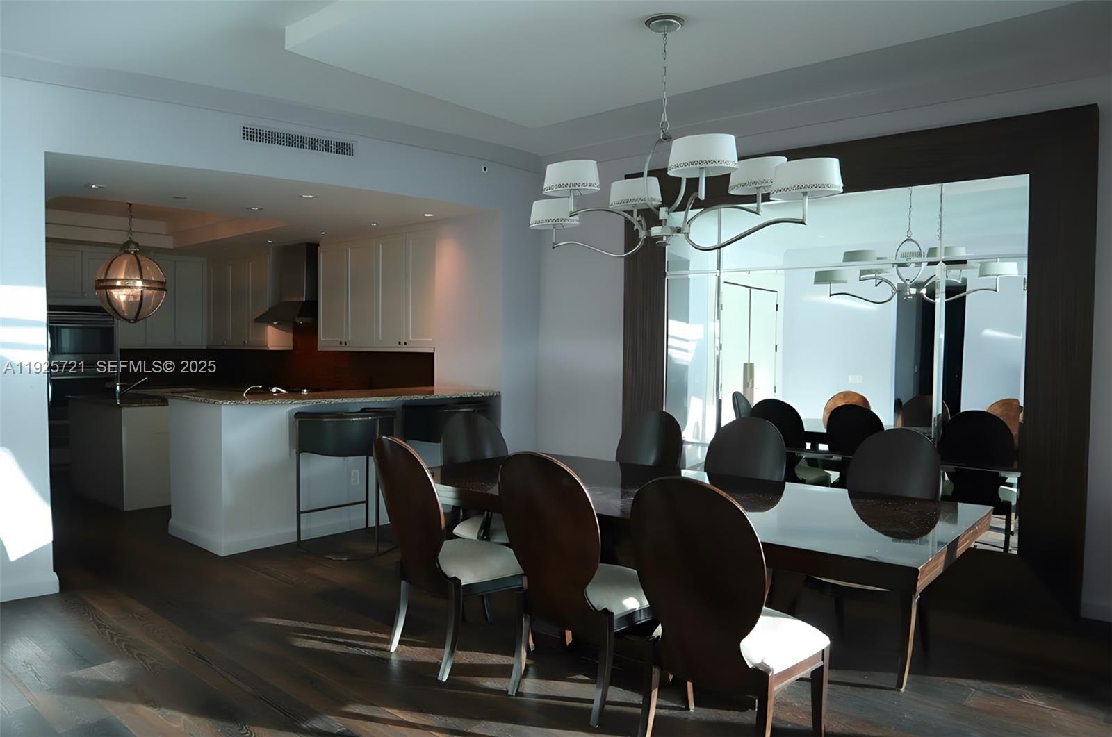 A dining room with a dark wood table, upholstered chairs, and a large wall mirror — 10295 Collins Ave # 1203, Bal Harbour FL 33154, BAL HARBOUR, FL