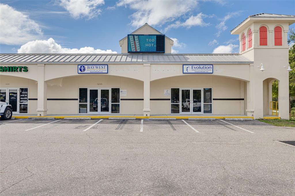 The exterior of a commercial strip mall building features two storefronts and a digital sign — 1033 W BAY DRIVE, LARGO, FL