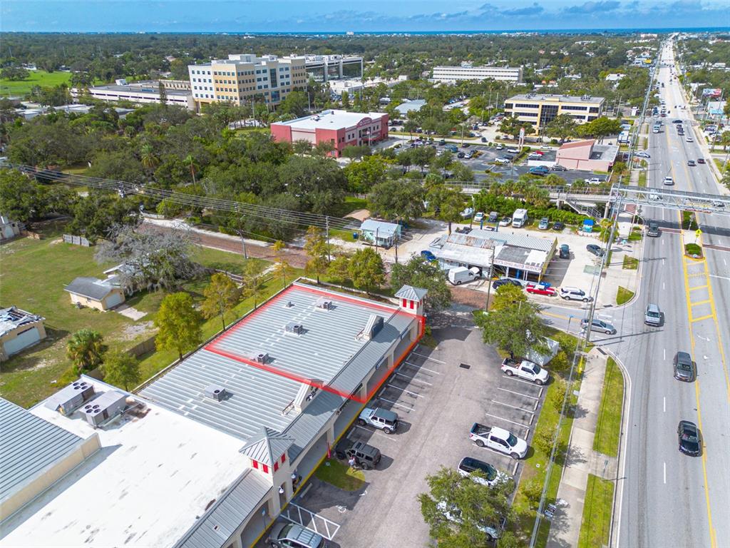 An aerial view shows a commercial building with a red outline on its roof — 1033 W BAY DRIVE, LARGO, FL