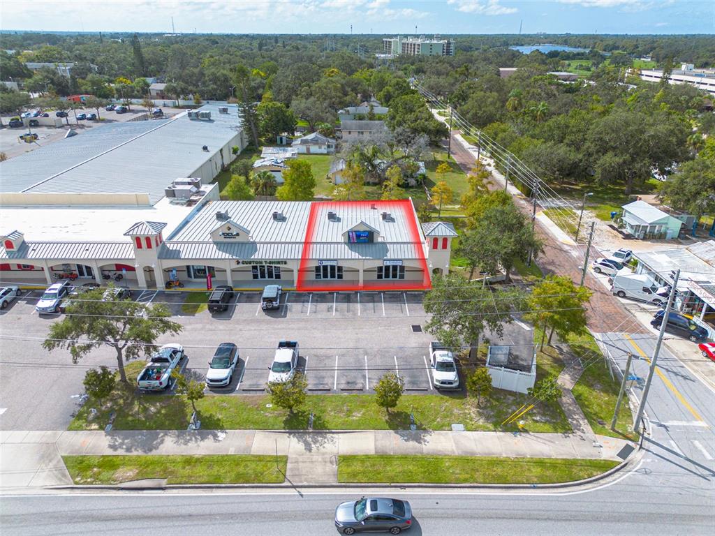 An aerial view shows a commercial strip mall with a highlighted storefront in the center — 1033 W BAY DRIVE, LARGO, FL