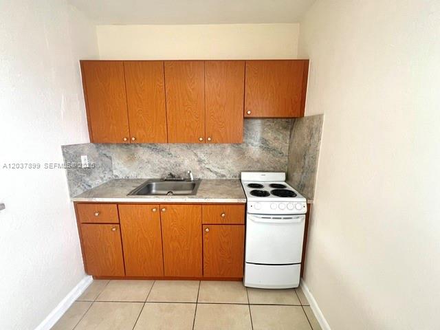 A small kitchen features wood cabinets, a stainless steel sink, and a white electric stove — 686 NE 85th St # 3B, Miami FL 33138, MIAMI, FL