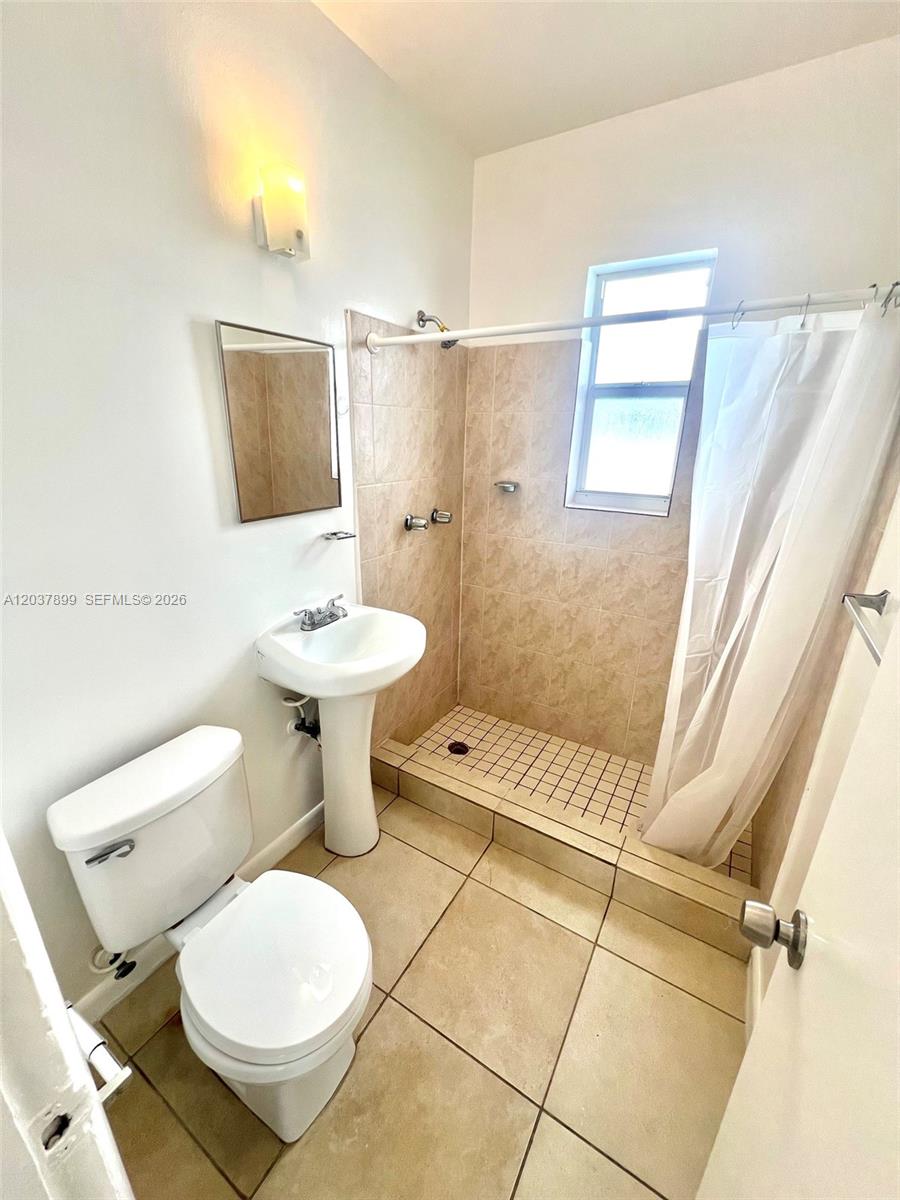This bathroom features a pedestal sink, a toilet, and a tiled walk-in shower — 686 NE 85th St # 3B, Miami FL 33138, MIAMI, FL