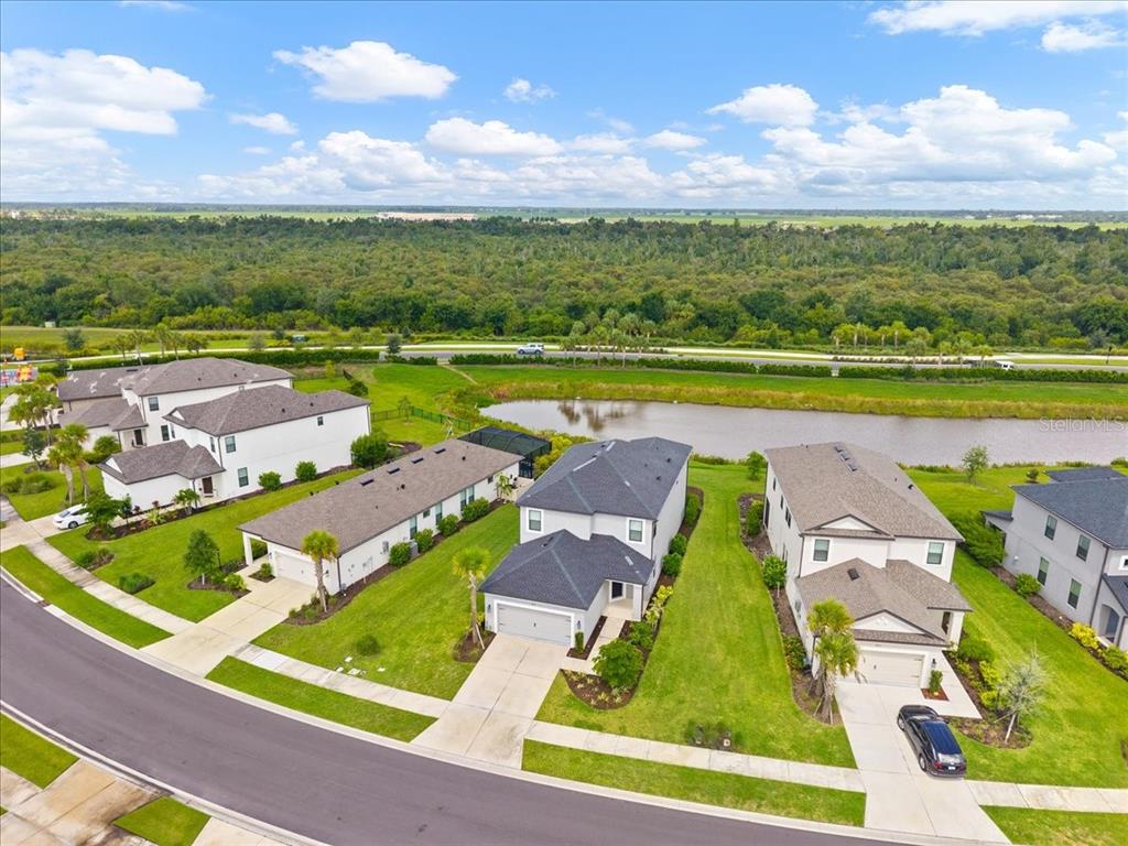 An aerial view shows suburban houses with driveways and lawns bordering a small pond — 9016 TEQUILA SUNRISE DRIVE, SARASOTA, FL