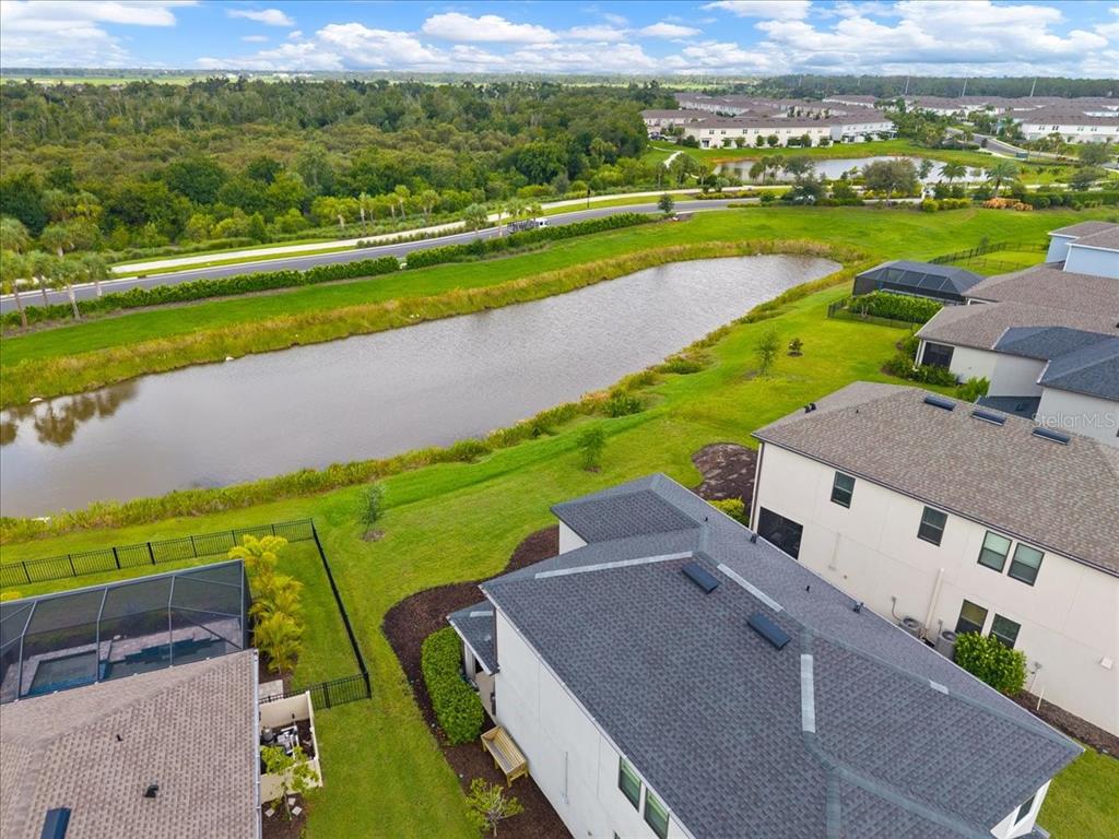 An aerial view shows a residential backyard with a pool enclosure overlooking a retention pond — 9016 TEQUILA SUNRISE DRIVE, SARASOTA, FL