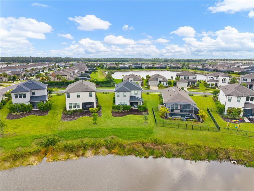 An aerial view shows several suburban houses with backyards facing a pond — 9016 TEQUILA SUNRISE DRIVE, SARASOTA, FL