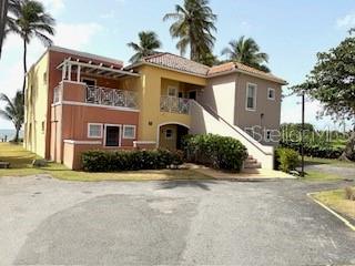 A two-story stucco building with balconies and palm trees sits near the ocean — CANDELERO DRIVE PALMAS DORADAS UNIT 519, HUMACAO, PR