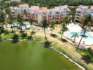 An aerial view shows a multi-story apartment complex with two swimming pools and a lake — CANDELERO DRIVE PALMAS DORADAS UNIT 519, HUMACAO, PR
