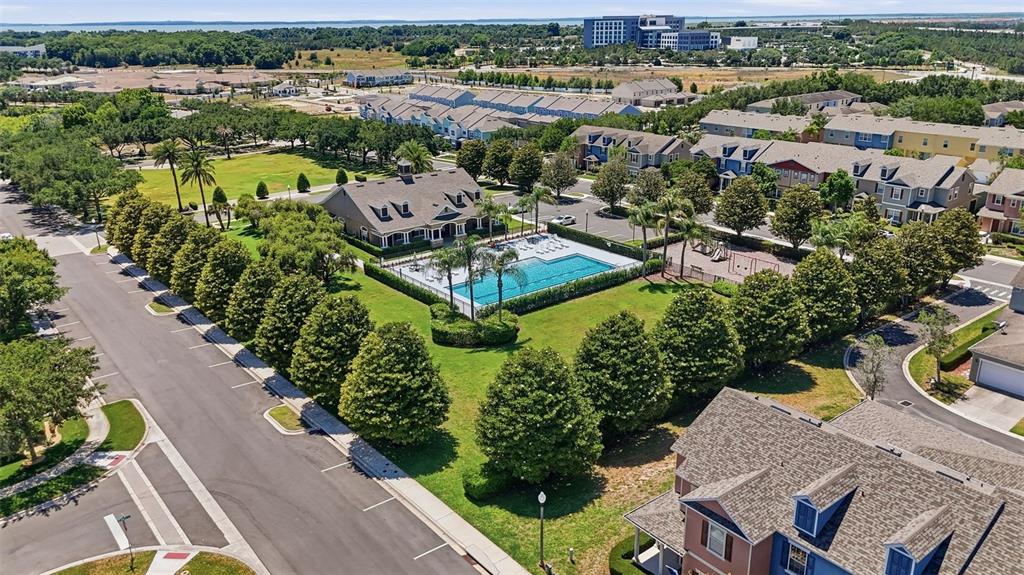 An aerial view shows a community swimming pool, clubhouse, and surrounding residential buildings — 2096 CORDAVILLE PLACE, APOPKA, FL