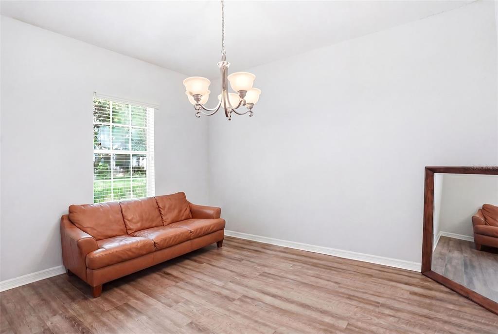 A room with light-colored walls, wood-look flooring, a leather sofa, and a hanging chandelier — 2096 CORDAVILLE PLACE, APOPKA, FL