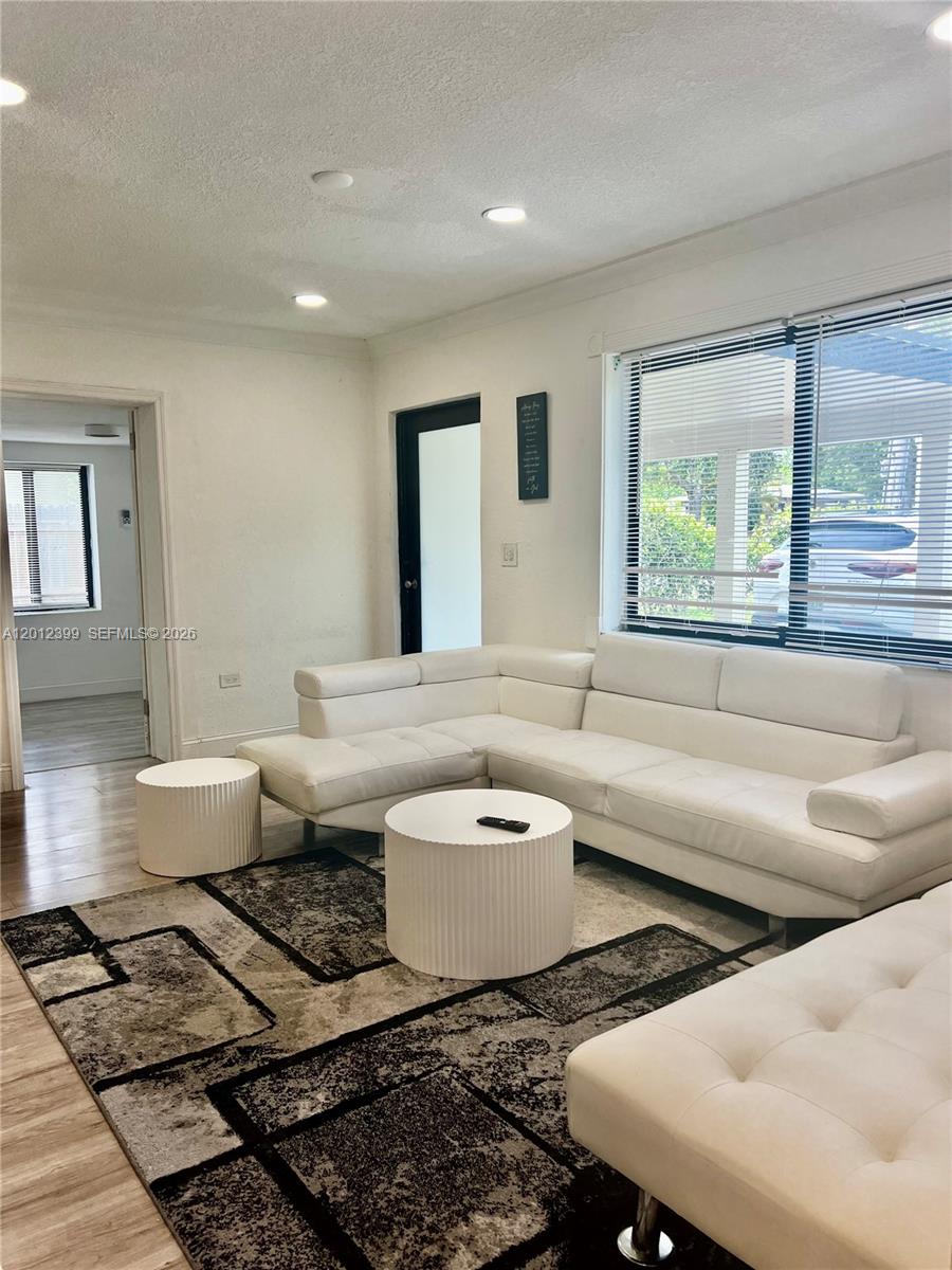A living room features a white sectional sofa, a round coffee table, and a patterned rug — 12040 N Miami Ave, North Miami FL 33168, NORTH MIAMI, FL