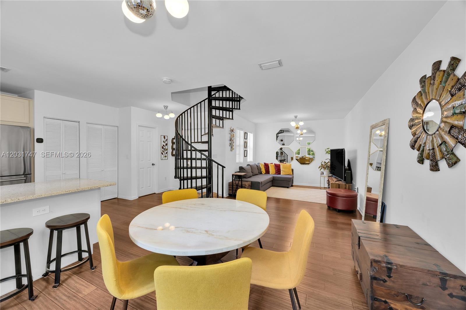 A living and dining area features a spiral staircase, yellow chairs, and wood flooring — 2850 Coconut Ave # 15, Miami FL 33133, MIAMI, FL