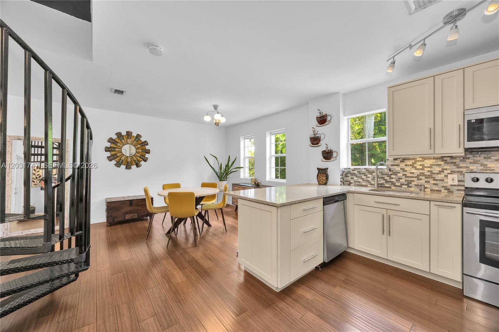 A kitchen and dining area features light-colored cabinetry, a spiral staircase, and yellow chairs — 2850 Coconut Ave # 15, Miami FL 33133, MIAMI, FL