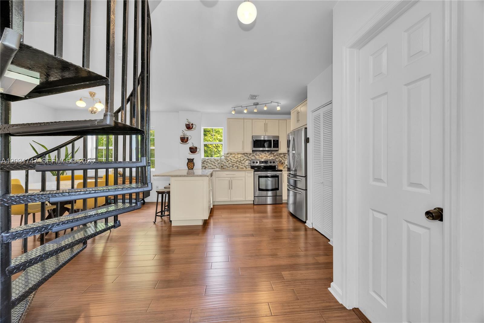 A kitchen features light cabinets, stainless steel appliances, and a spiral staircase in the foreground — 2850 Coconut Ave # 15, Miami FL 33133, MIAMI, FL