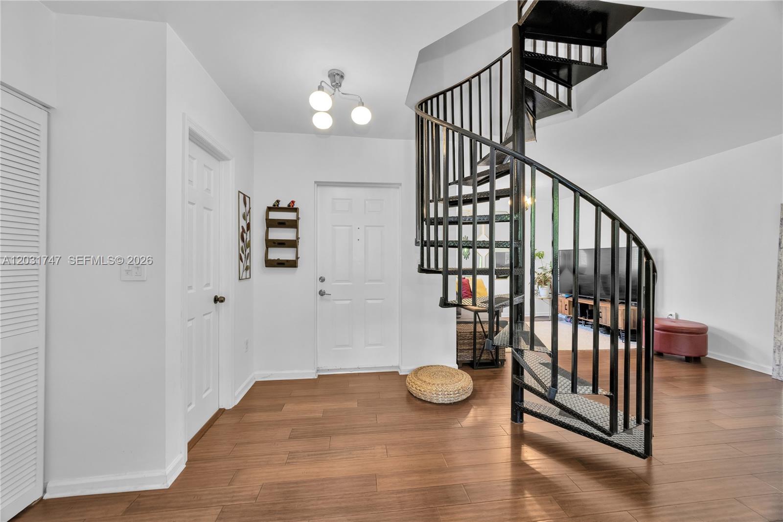 An entryway features wood-look flooring, a white door, and a black metal spiral staircase — 2850 Coconut Ave # 15, Miami FL 33133, MIAMI, FL