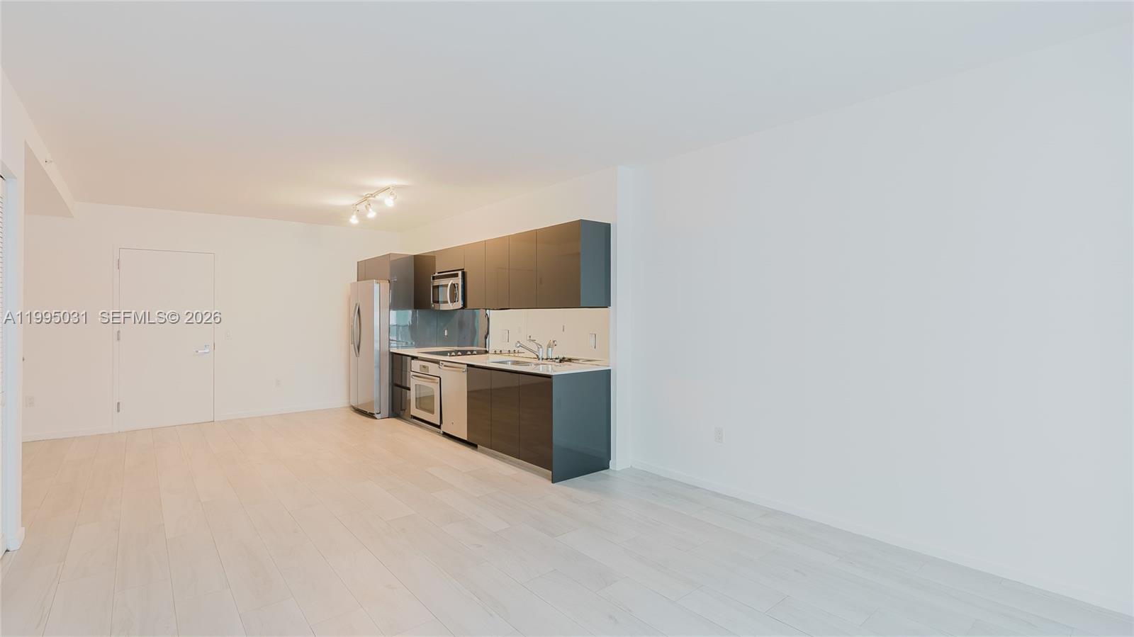 A modern kitchen features dark gray cabinetry, stainless steel appliances, and light wood-look flooring — 31 SE 6th St # 1906, Miami FL 33131, MIAMI, FL