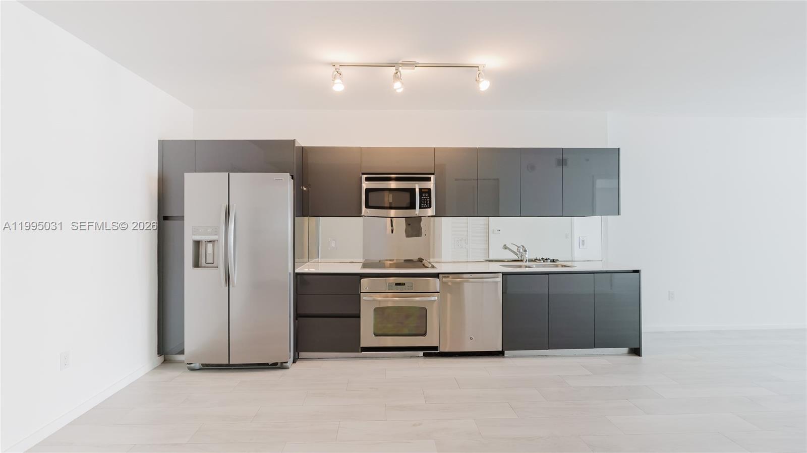 A modern kitchen features gray flat-panel cabinets, stainless steel appliances, and a mirrored backsplash — 31 SE 6th St # 1906, Miami FL 33131, MIAMI, FL