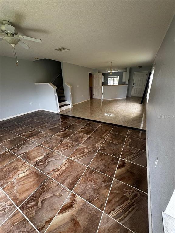 A living room with brown marble-patterned tile flooring leads to a kitchen and staircase — 6913 MARBLE FAWN PLACE, RIVERVIEW, FL