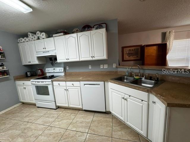 A kitchen features white cabinets, tan countertops, a white stove, and a stainless steel sink — 6913 MARBLE FAWN PLACE, RIVERVIEW, FL