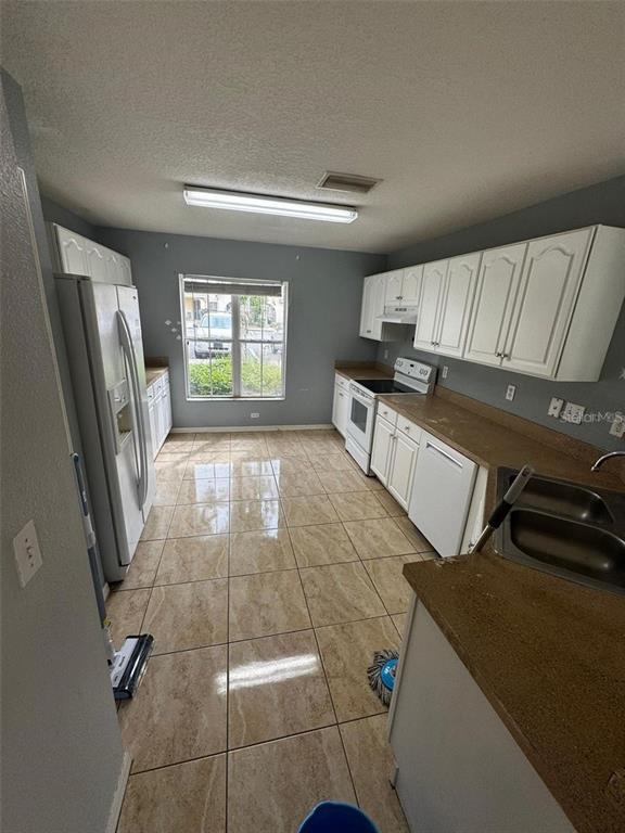 A kitchen with white cabinets, tan countertops, tile flooring, and a window overlooking the outdoors — 6913 MARBLE FAWN PLACE, RIVERVIEW, FL