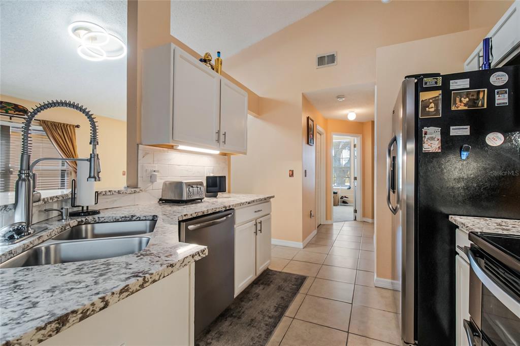 A kitchen features white cabinets, granite countertops, stainless steel appliances, and a tile floor — 134 LANGHAM DRIVE, DAVENPORT, FL