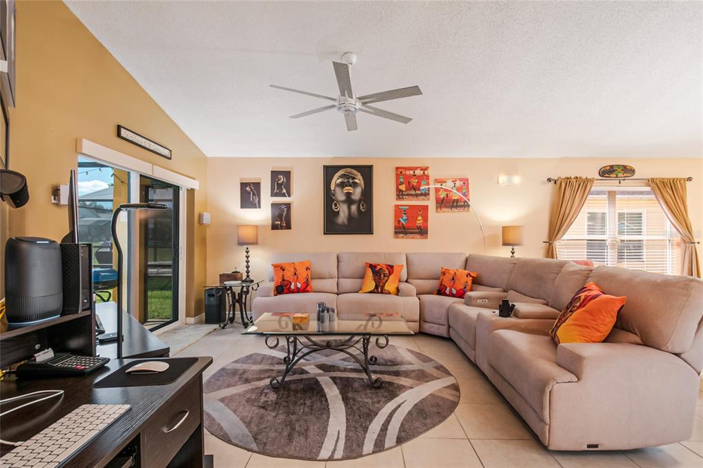 A living room features a large sectional sofa, a round rug, and wall art — 134 LANGHAM DRIVE, DAVENPORT, FL