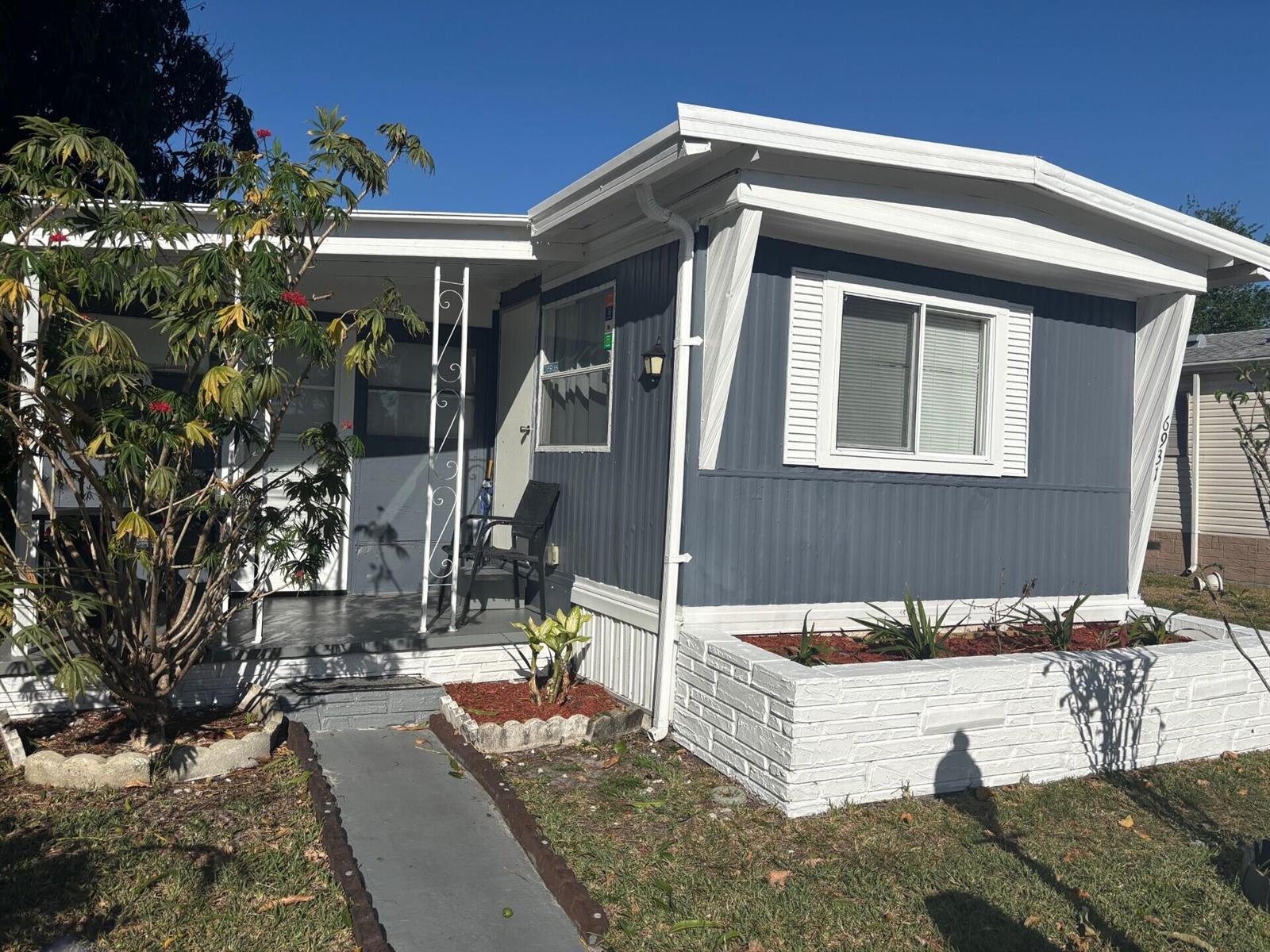 A blue mobile home with white trim, a covered porch, and a white brick planter — 6931 NW 45th Terrace, Coconut Creek FL 33073, COCONUT CREEK, FL