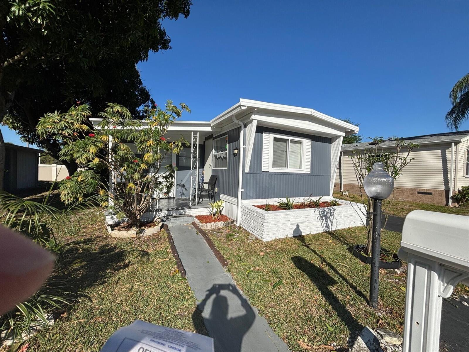 A blue mobile home with a white roof, front porch, and a white brick planter — 6931 NW 45th Terrace, Coconut Creek FL 33073, COCONUT CREEK, FL