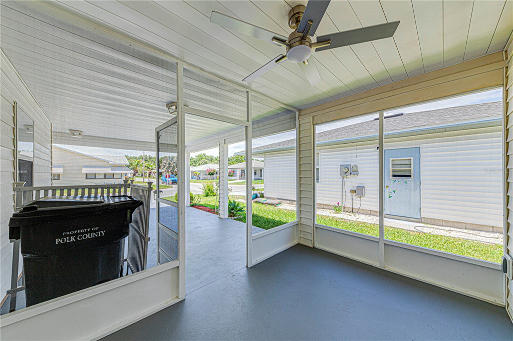 A screened-in porch features a ceiling fan, gray flooring, and views of neighboring houses — 1618 COLONNADES CIRCLE N, LAKELAND, FL