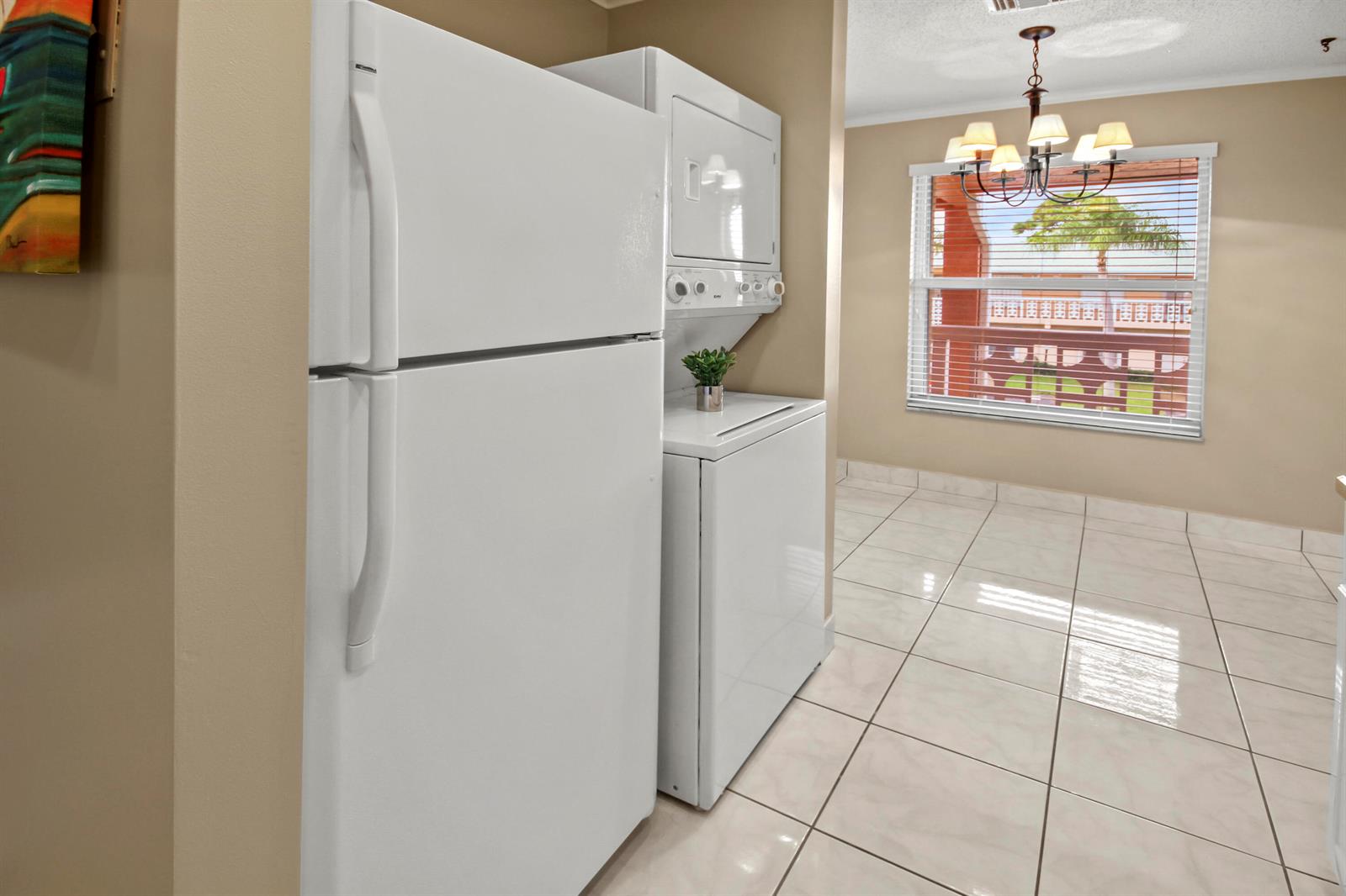 A white refrigerator and stacked laundry unit sit in a tiled room with a window — 1421 NW 20th Avenue # 204, Delray Beach FL 33445, DELRAY BEACH, FL