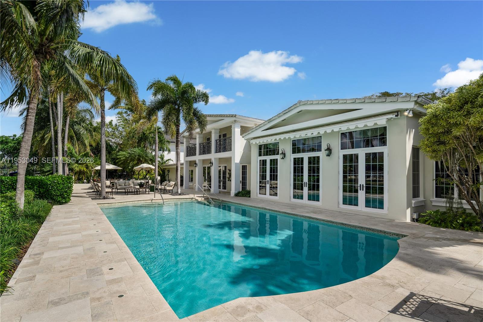 A swimming pool sits in front of a two-story house with a patio and palm trees — 4620 Granada Blvd, Coral Gables FL 33146, CORAL GABLES, FL