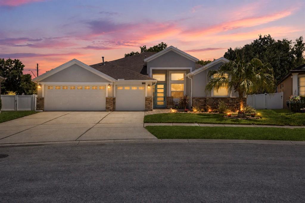 A single-story suburban house with a three-car garage and a light blue front door — 27901 SUMMER PLACE DRIVE, WESLEY CHAPEL, FL