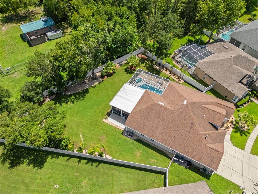 An aerial view shows a house with a screened pool, a large lawn, and fencing — 27901 SUMMER PLACE DRIVE, WESLEY CHAPEL, FL