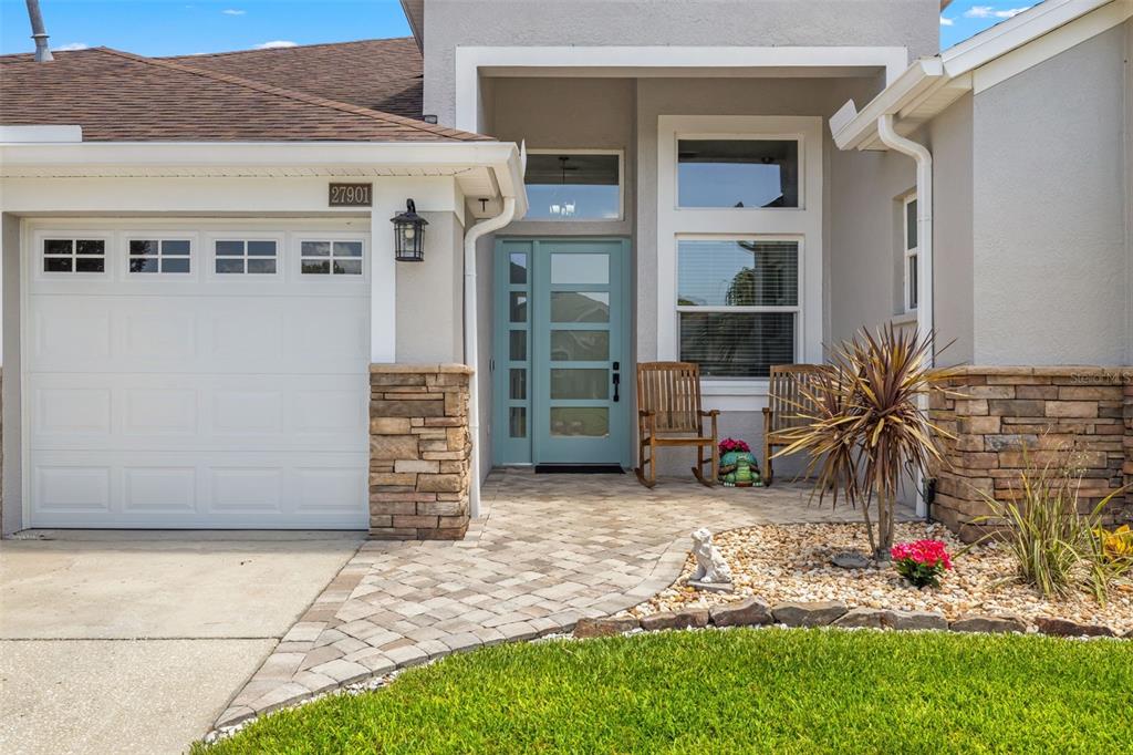 The exterior of a house features a light blue front door, stone accents, and a walkway — 27901 SUMMER PLACE DRIVE, WESLEY CHAPEL, FL