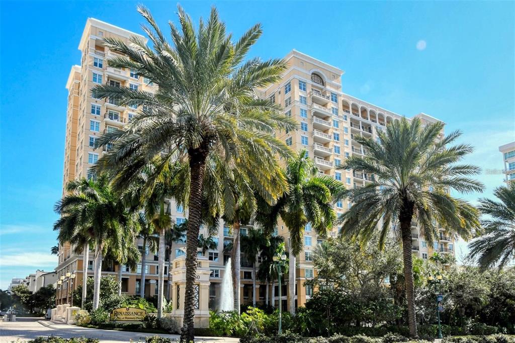 A tall, tan multi-story apartment building is surrounded by palm trees and a water fountain — 750 N TAMIAMI TRAIL UNIT 916, SARASOTA, FL