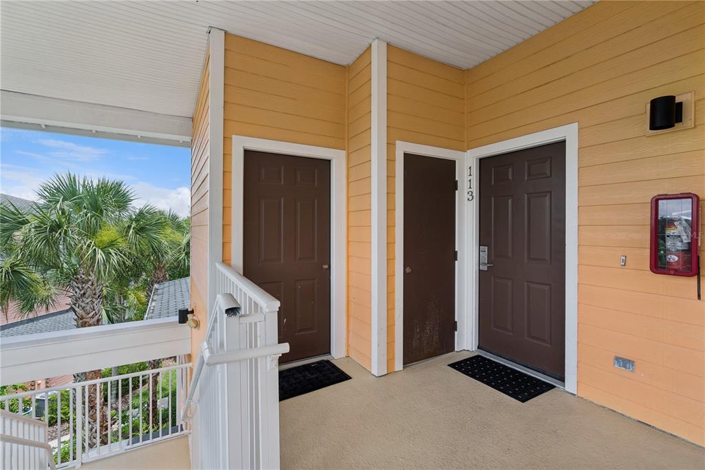 An outdoor apartment landing features two brown doors, one marked 113, and a fire extinguisher — 113 ANDROS AVENUE UNIT B16 U113, DAVENPORT, FL