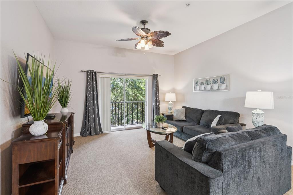 A living room features dark gray sofas, a glass coffee table, and a sliding glass door — 113 ANDROS AVENUE UNIT B16 U113, DAVENPORT, FL