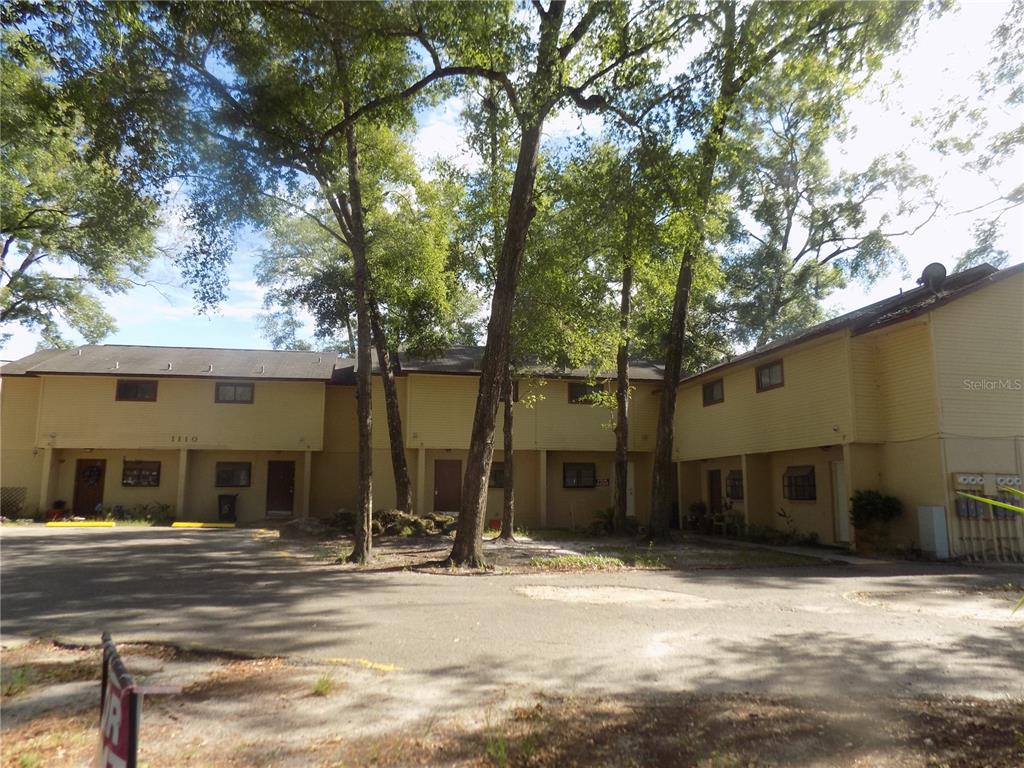 A two-story yellow apartment building with multiple entrances sits behind a paved parking area — 1110 SW 62 TERRACE UNIT A,B,C,D,E and F, GAINESVILLE, FL