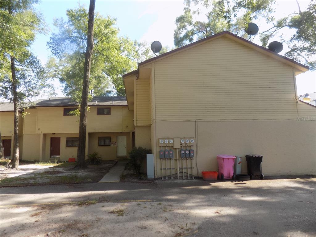 An exterior view of a two-story apartment building with yellow siding and utility meters — 1110 SW 62 TERRACE UNIT A,B,C,D,E and F, GAINESVILLE, FL