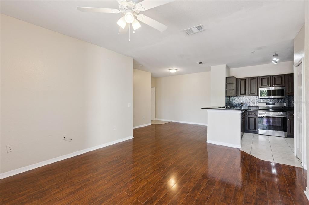 An open-concept living area with hardwood floors leads to a kitchen with dark wood cabinets — 1460 LAKE SHADOW CIRCLE UNIT 7207, MAITLAND, FL