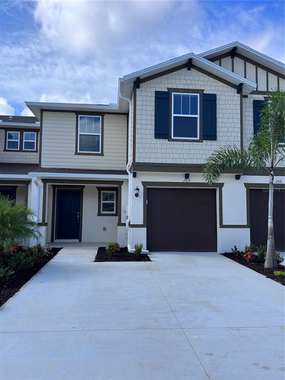 A two-story townhouse exterior features a brown garage door, dark shutters, and a concrete driveway — 15031 CASPIAN TERN COURT UNIT 105, NORTH FORT MYERS, FL