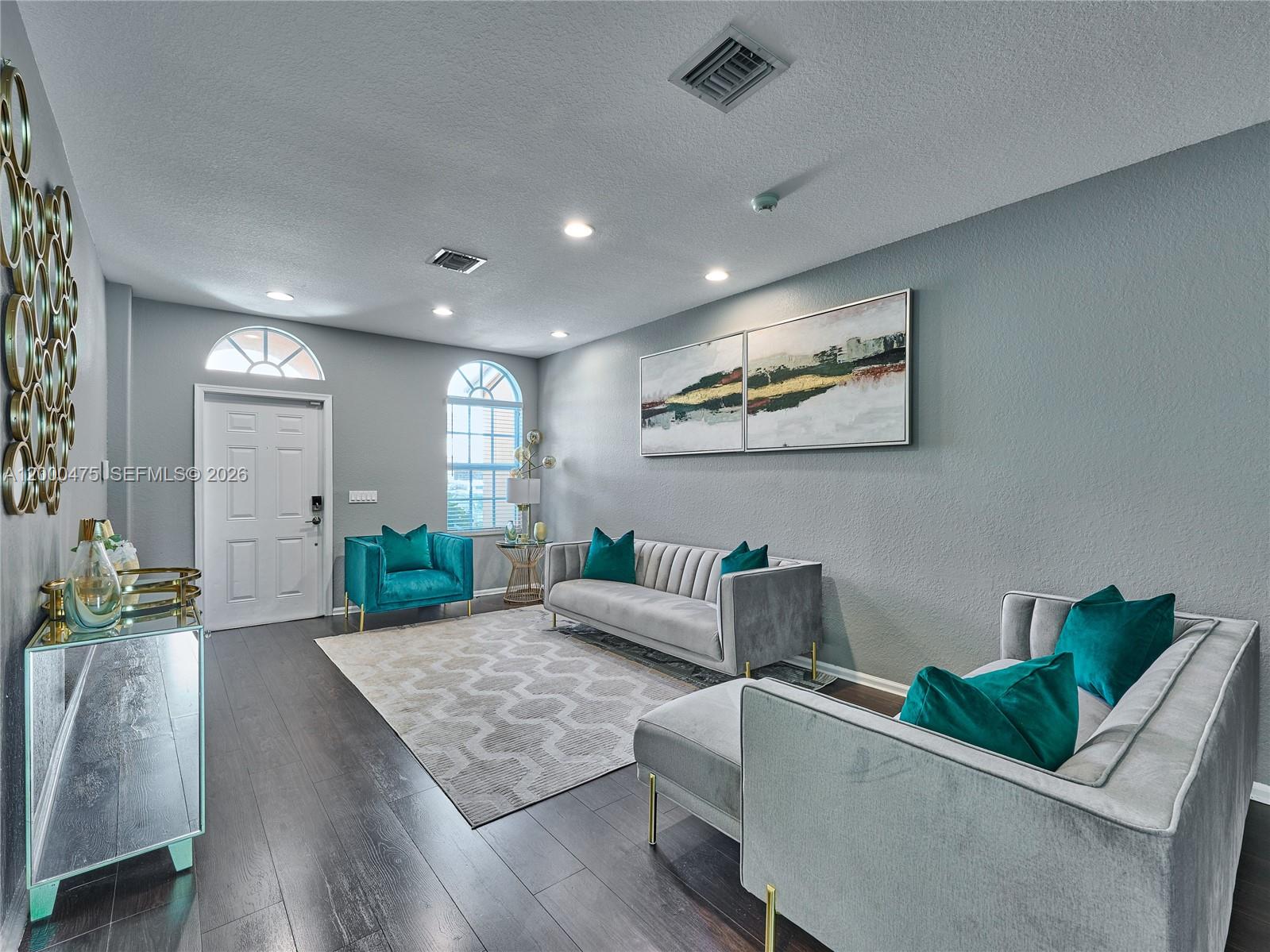 A living room features gray walls, dark wood floors, velvet furniture, and a geometric rug — 7430 Briella Dr, Boynton Beach FL 33437, BOYNTON BEACH, FL