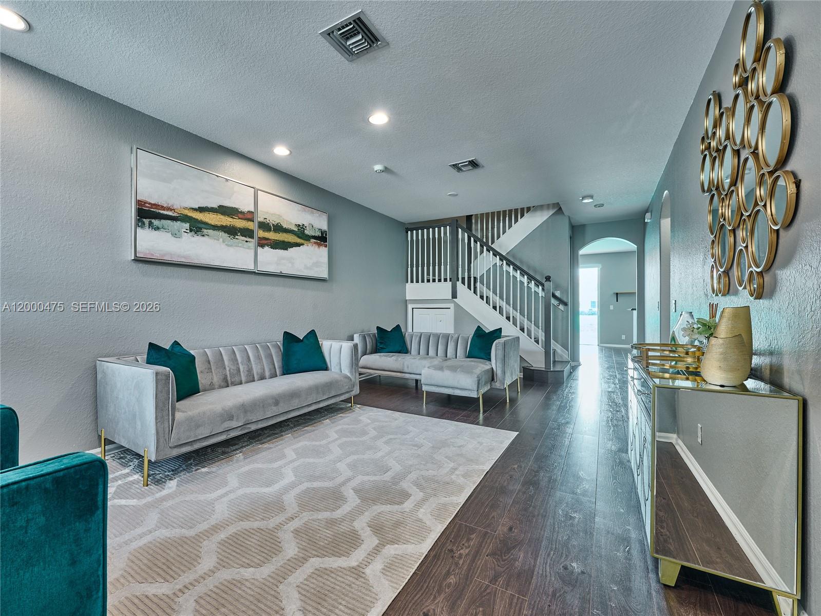 A living room features two grey velvet sofas, a geometric rug, and gold-framed wall mirrors — 7430 Briella Dr, Boynton Beach FL 33437, BOYNTON BEACH, FL