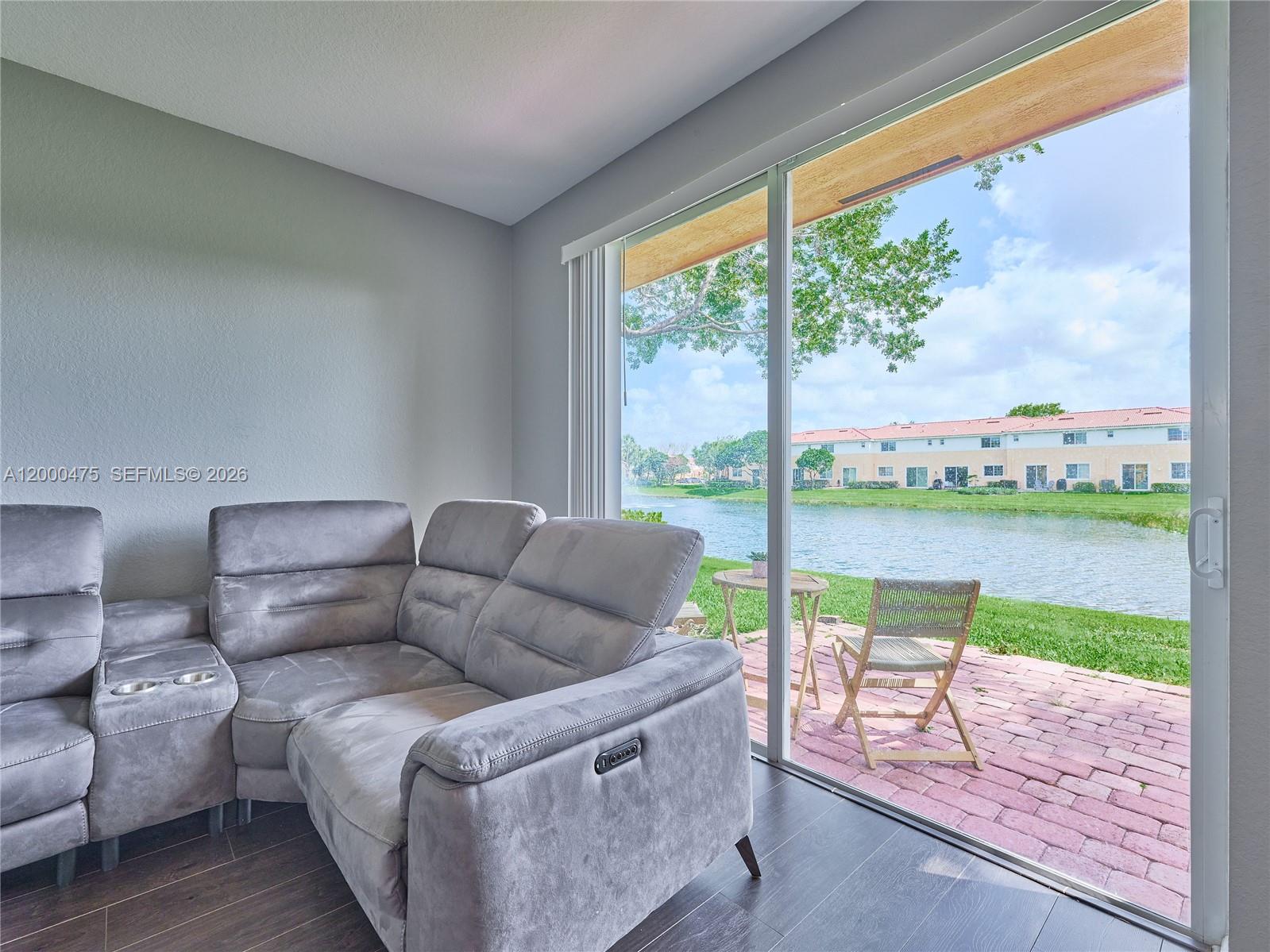 A gray reclining sofa sits on dark wood floors next to a sliding glass door — 7430 Briella Dr, Boynton Beach FL 33437, BOYNTON BEACH, FL