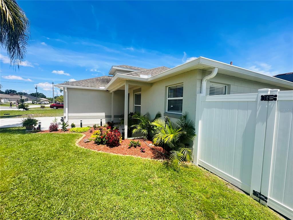 A side view of a house exterior with a white vinyl fence and landscaping — 340 EDGEWOOD COURT, KISSIMMEE, FL