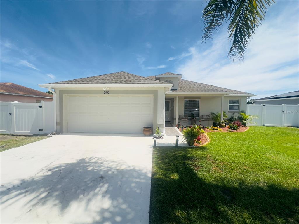 A single-story house with a two-car garage, a white fence, and a grassy front yard — 340 EDGEWOOD COURT, KISSIMMEE, FL