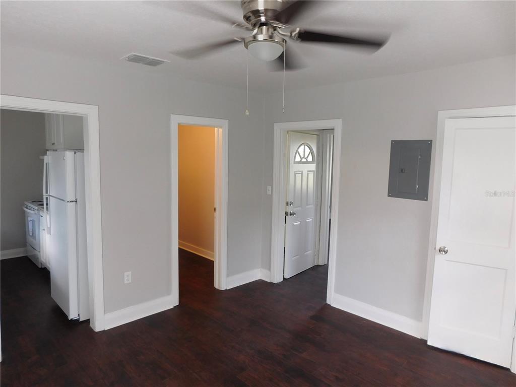 A room with dark wood flooring, gray walls, a ceiling fan, and multiple doorways — 7383 WAVERLY ROAD UNIT #1, LAKE WALES, FL
