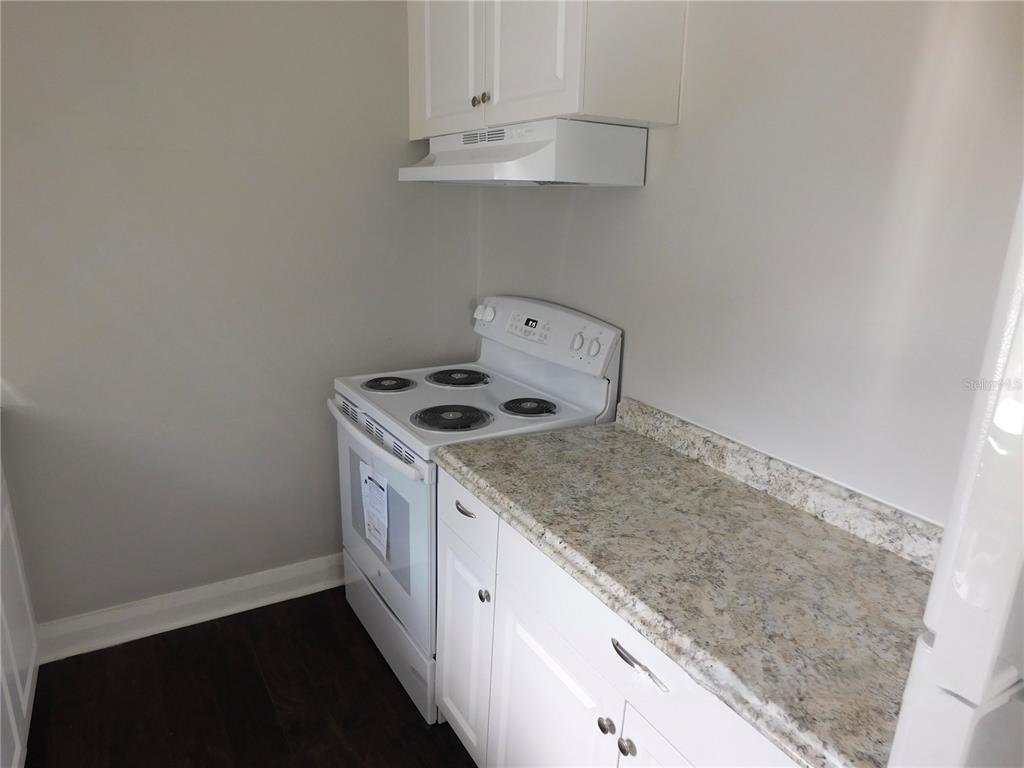 A kitchen features white cabinets, a white electric stove, and a speckled laminate countertop — 7383 WAVERLY ROAD UNIT #1, LAKE WALES, FL