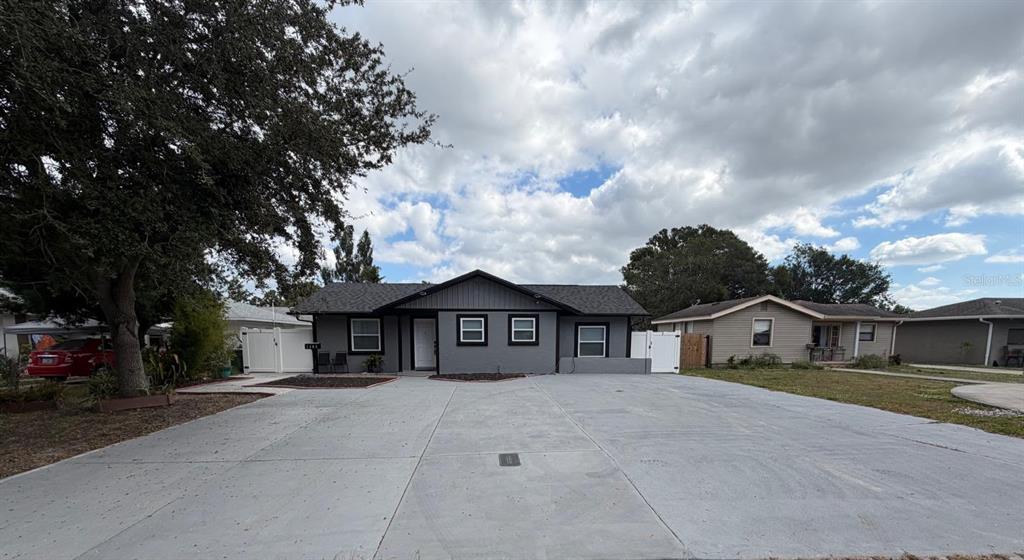 A gray single-story house with a large concrete driveway and a white side gate — 1305 29TH STREET W, BRADENTON, FL